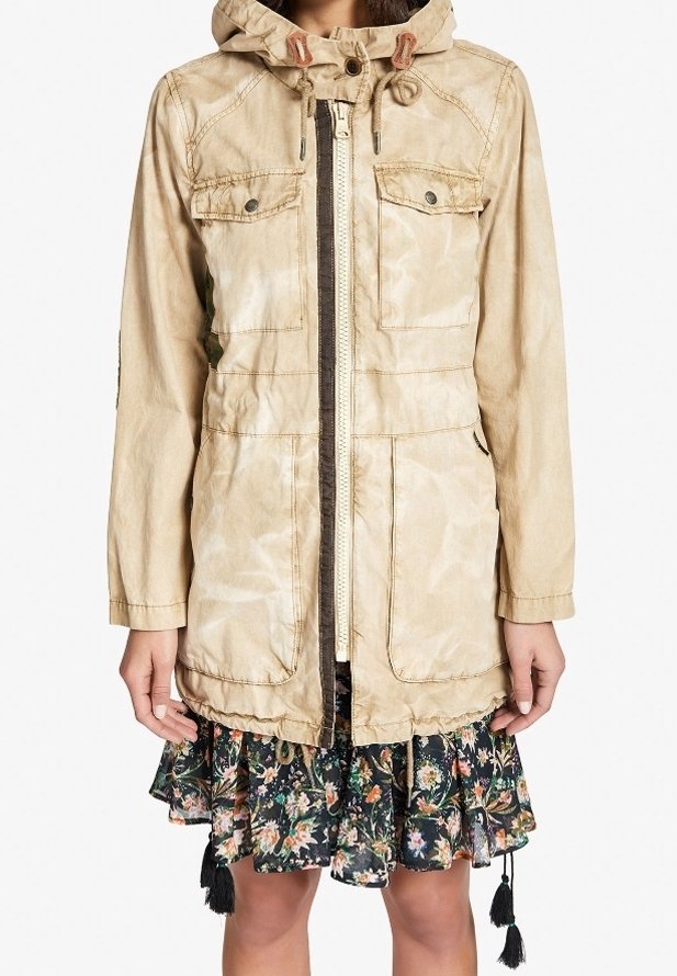Beżowa kurtka z kapturem, zapinana na zamek, z dwoma kieszeniami na piersiach i regulowanymi sznurkami. Posiada woskową fakturę i lekki, casualowy design.