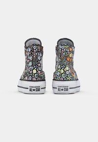 Visoke Converse tenisice s cvjetnim uzorkom u raznim bojama na crnoj podlozi. Bijela gumena potplat s logotipom branda na peti.