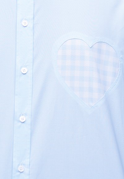 Ανοιχτό μπλε πουκάμισο με καρό σχέδιο, λευκά κουμπιά και τσέπη σε σχήμα καρδιάς με μεγαλύτερο καρό μοτίβο στο στήθος.