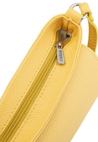 Borsa in pelle gialla con superficie texture, dotata di chiusura a zip con un tirante in argento etichettato "RYŁKO" e una maniglia robusta.