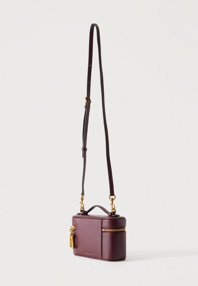 Petit sac bandoulière rectangulaire en cuir violet foncé avec des fermetures éclair dorées, une poignée supérieure et une bandoulière réglable.