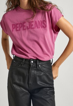 Lyserød bomulds t-shirt med "PEPE JEANS" i udskåret skrifttype, parret med sorte højhalsede denim jeans for et afslappet look.