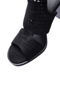 Sandalo nero con punta aperta e superiore in suede perforato. Presenta una soletta morbida e un tacco rotondo elegante. La soletta è liscia e nera.