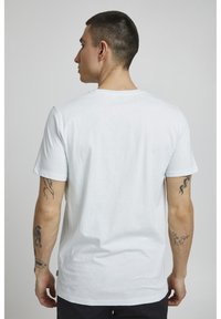 Hvid bomulds T-shirt med korteærmer, standard rund halsudskæring, glat tekstur og subtile syninger, vist fra bagsiden.