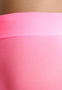 Różowe legginsy dopasowane, o gładkiej, elastycznej strukturze. Posiadają szeroki pas i bezszwowy design. Odpowiednie do noszenia aktywnego.