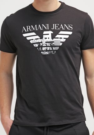 T-shirt en coton noir avec le logo "Armani Jeans" en blanc. Le design comprend un graphique de rayures horizontales et une imagerie urbaine.