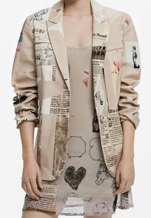 Beżowa marynarka i pasująca sukienka z podwiniętymi rękawami, ozdobione nadrukiem z tekstem gazetowym, szkicami, sercami i obrazami architektonicznymi.