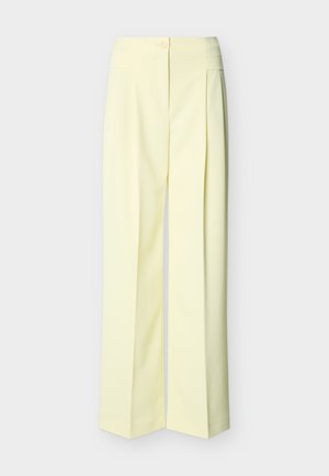 Ανοιχτό κίτρινο παντελόνι ευρέος ποδιού με ψηλή μέση, κλείσιμο με κουμπί και φερμουάρ μπροστά, και πιέτες, σε μονόχρωμο φόντο.