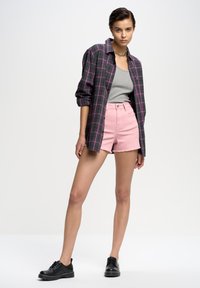 Pelēka un rozā raiba krekls virs pelēka bezmugurkaula krekla, apvienots ar gaiši rozā džinsa šortiem un melniem kurpju zābakiem. Gludas auduma, ikdienišķs stils.