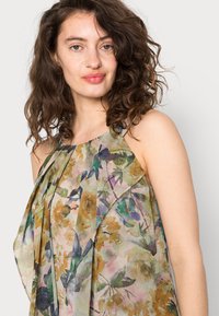 Vestido floral leve com um padrão multicolorido em verdes, castanhos e amarelos. Feito de um tecido leve, tem um corte descontraído.