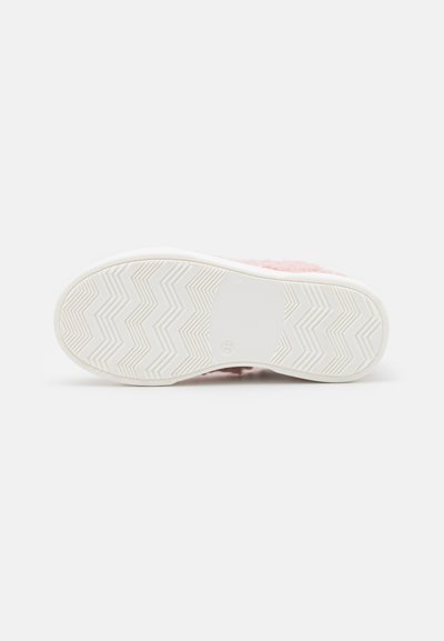 Chinelo rosa peludo com sola de borracha branca, apresentando um padrão de piso em zigzag. O interior tem uma textura macia para conforto.