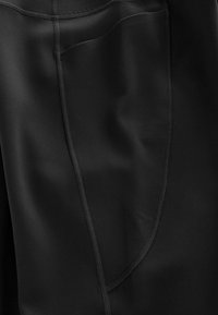 Leggings sportivi negri cu o textură netedă, având un singur buzunar lateral și cusături plate pentru un design aerodinamic.