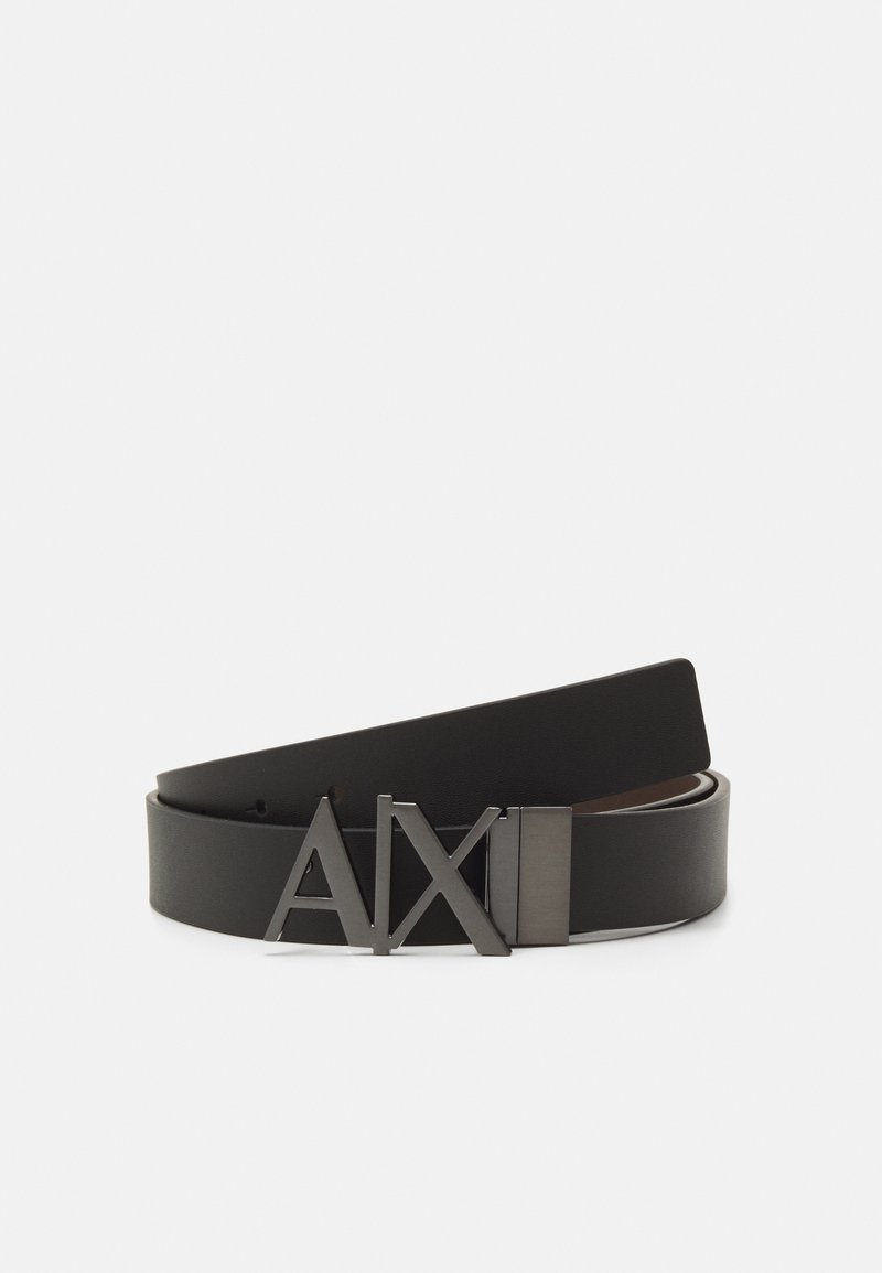 Cinturón de cuero negro con una textura suave, que presenta una hebilla de metal adornada con las letras "AXI" en un diseño audaz.