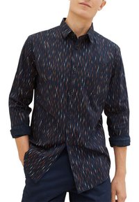 Chemise boutonnée bleu marine avec un motif répété de lignes vives orange, blanches et bleu clair. Dotée d'un col et de manches retroussées.