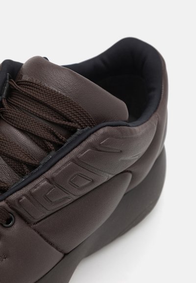 Brown leather shoe with textured upper, round toe, and padded collar. Features a lace-up design and embossed branding on the side.