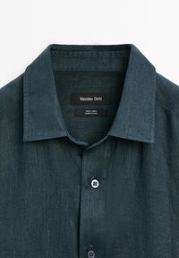 Dark green linen shirt with a collar, featuring a button front and a smooth texture. Label reads "Massimo Dutti" and "100% Linen."