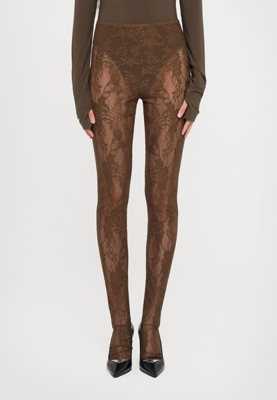 Brune blonde leggings med et blomstermuster, høj talje-design og gennemsigtig tekstur, parret med sorte spidse hæle.