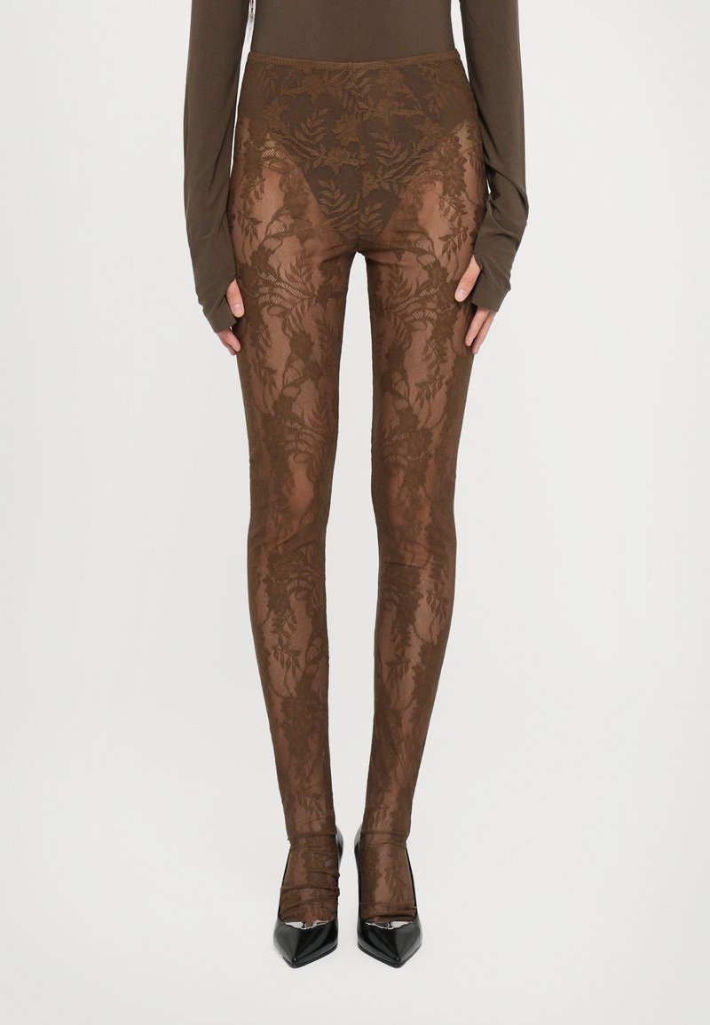 Brune blondeleggings med blomstermønster, høy midje-design, og gjennomsiktig tekstur, kombinert med svarte spisse hæler.
