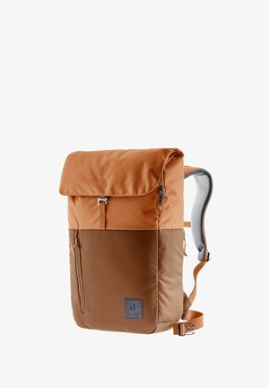 La mochila de tela marrón cuenta con un cierre enrollable, un bolsillo lateral con cremallera, correas de hombro acolchadas y un parche con el logo en el frente.
