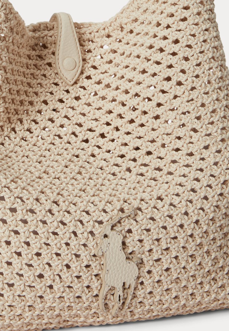 Sac beige en crochet avec une lanière boutonnée en cuir et un logo en cuir représentant un joueur de polo à cheval cousu sur le devant.
