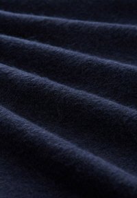 Granatowa wełniana tkanina o miękkiej, teksturowanej powierzchni, prezentująca delikatne fale i włóknisty wygląd.