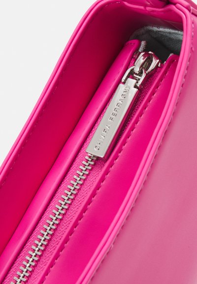 Borsa a tracolla in ecopelle rosa con una cerniera silver, dotata di un'etichetta con il marchio. L'interno è liscio e foderato in un tessuto morbido.