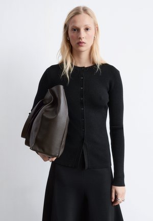 Black ribbed cardigan with long sleeves and button closure, paired with a structured dark brown leather bag and a black skirt.