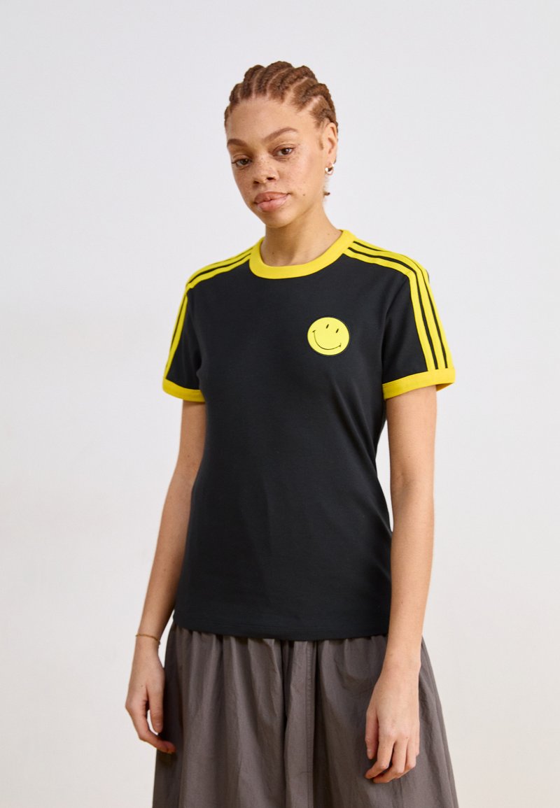 Black t-shirt with yellow neckline and sleeves, featuring three yellow stripes on each shoulder and a yellow smiley face logo on the chest.