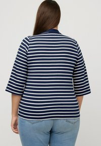 Marineblau-weiß gestreiftes Shirt mit Dreiviertelärmeln. Weicher, elastischer Stoff. Rundhalsausschnitt, taillierte Form und lässiges Design.