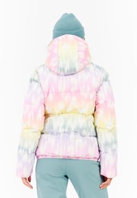 Gefütterte Jacke mit einem pastellfarbigen Batikmuster in Pink, Gelb und Blau. Verfügt über eine Kapuze und elastische Bündchen. Getragen mit hellblauen Hosen.
