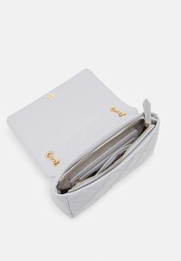 Borsa grigia trapuntata con ferrature dorate, dotata di un scomparto con cerniera e di una tasca aperta. Texture liscia e forma strutturata.