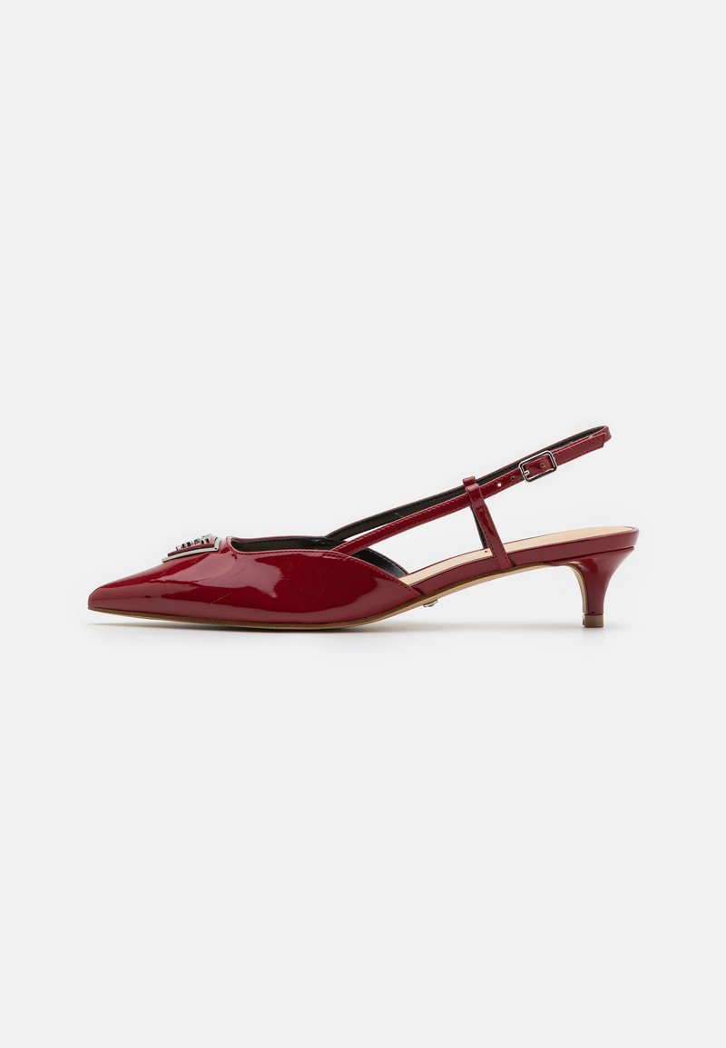 Crvene lakirane slingback cipele s šiljastim nosom, niskom potpeticom, podesivim remenom i ukrasnom srebrnom kopčom na prednjem dijelu.