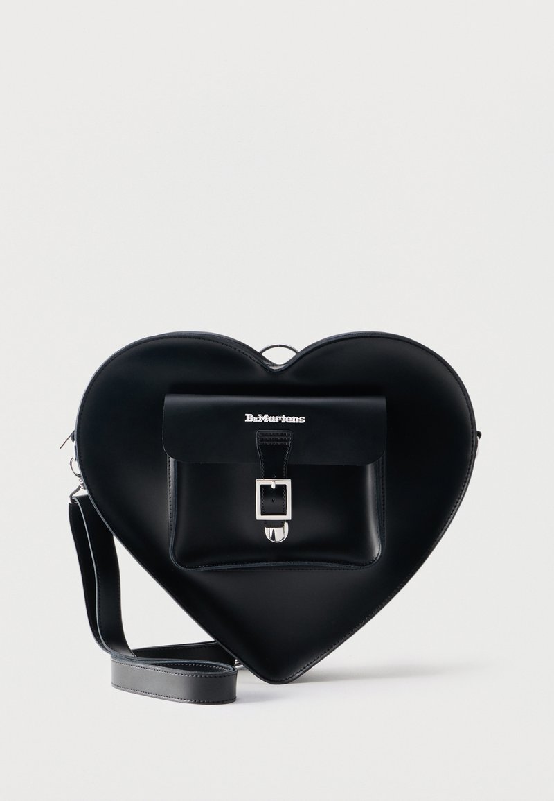Black leather heart-shaped handbag with front buckle pocket and adjustable shoulder strap, Dr. Martens logo on pocket flap.