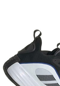 Zapatilla deportiva negra con parte superior de malla, entresuela blanca, suela de goma texturizada y acentos azules. Cuenta con lazos en el talón para facilitar el calzado.