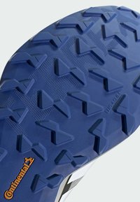 Suola della scarpa in gomma blu scuro con tasselli di trazione multidirezionali. Presenta una superficie testurizzata e il logo "Continental" in arancione.