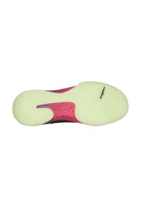 La suela del zapato presenta un diseño texturizado en negro y rosa con un fondo verdoso-amarillo. Incluye un logotipo y un patrón de banda de rodadura distintivo.