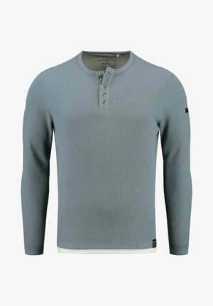 Chemise à manches longues de style henley en texture côtelée bleu clair, dotée de trois boutons au cou et d'un accent blanc au bas.