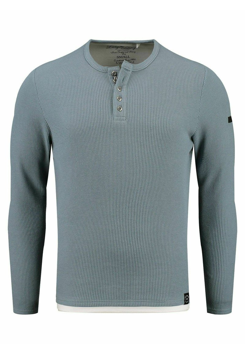 Maglietta a maniche lunghe in stile henley di colore azzurro chiaro con texture a righe, caratterizzata da tre bottoni al collo e un accento bianco all'orlo.