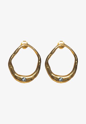 Boucles d'oreilles en forme de créole en ton doré avec une texture organique, présentant un petit accent de pierre précieuse bleue sur chaque boucle.