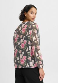 Blomstret bluse med en semi-gennemsigtig, grå baggrund. Har mønstre af lyserøde roser og hvide magnolier. Lange ærmer, afrundet kant, letvægtsstof.