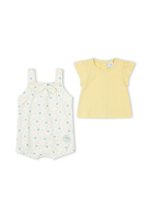 Camiseta amarilla de manga corta para bebé y peto blanco con flores en tonos verde azulado y amarillo, ambos extendidos sobre fondo blanco.