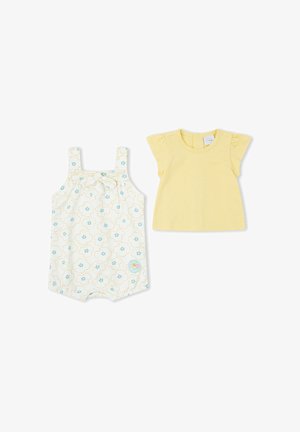 Camiseta amarilla de manga corta para bebé y peto blanco con flores en tonos verde azulado y amarillo, ambos extendidos sobre fondo blanco.