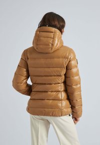 Giubbotto puffo marrone con cappuccio, caratterizzato da sezioni verticali trapuntate, texture liscia e lucida, e dettagli con zip sui lati.