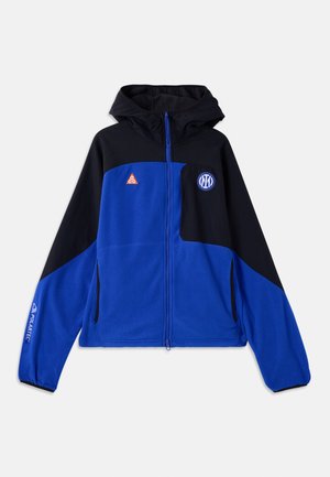 Modra in črna flis jakna s kapuco, z zadrgo po celotni dolžini, dvema stranskima žepoma ter logotipi na prsih in levi rokavu.