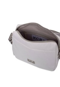 Witte nylon crossbody tas met een ritsvak, lichtgrijze binnenkant, zilverkleurige hardware en een logo aan de voorkant.