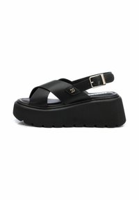 Sandalias de plataforma negras con diseño de tiras entrecruzadas, hebilla ajustable y suela de goma texturizada. Fabricadas en material sintético.