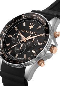 Orologio cronografo con quadrante nero, dettagli in oro rosa, cassa in acciaio inossidabile e cinturino in gomma. Presenta tachimetro e tre sottonicchie.