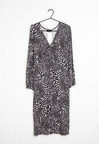 Mustavalkoinen kuviollinen mekko, jossa on syvä V-pääntie, pitkät hihat ja kerroksellinen etuosa, joka sisältää sekoituksen orgaanisia muotoja.