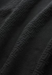 Schwarzer Stoff mit einem strukturierten Muster aus ineinandergreifenden Linien. Das weiche, gewebte Material weist eine glatte Oberfläche und einen subtilen Glanz auf.