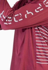 Bordowa sportowa koszulka z długim rękawem, ozdobiona białym tekstem graficznym i paskami wzdłuż boku. Wykonana z gładkiego, lekkiego materiału.